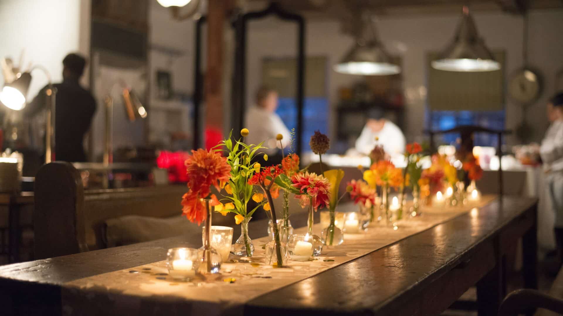 Florals and candles on a runner down a wooden kitchen table